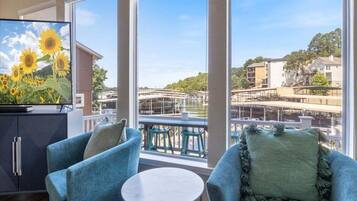 Un balcon donnant sur un pont et des immeubles, aménagé avec deux chaises bleues et une petite table.