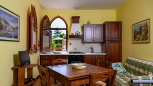 A kitchen with wooden cabinets, a dining table, and chairs. There is a laptop on a small table next to the kitchen. - Il Ciliegio ,'le Calme et la Tranquillité Sont Notre Carte de Visite' (Castelbuono)