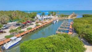 A canal with boats docked, a building with a blue roof, and a clear view of the ocean. - Florida Keys Getaway - Slps 4 -  Ocean View (Tavernier)