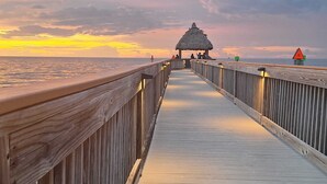 A wooden pier leading to a thatched-roof structure with a warning sign and a lifebuoy. - Florida Keys Getaway - Slps 4 -  Ocean View (Tavernier)