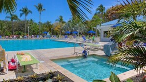 A pool area with lounge chairs, a lifeguard stand, and palm trees. - Toes in the Sand - 2 Bedroom Condo Sleeps 4 (Tavernier)