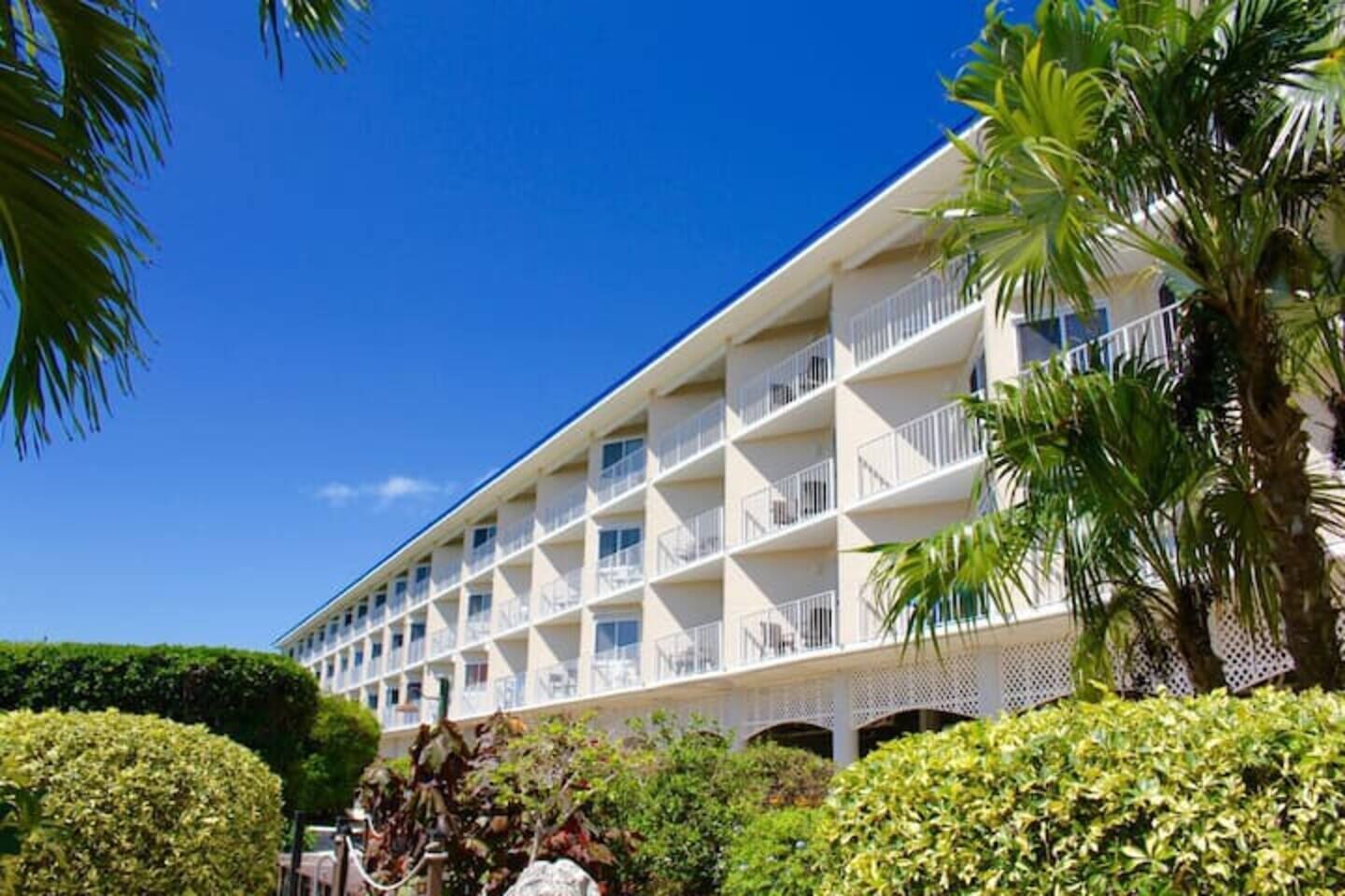 Un hôtel à plusieurs étages, doté de balcons, avec un ciel d’un bleu éclatant.