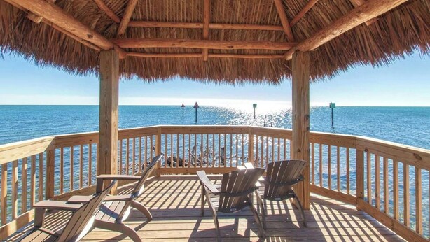 A wooden deck with a thatched roof, overlooking the sea. - Toes in the Sand - 2 Bedroom Condo Sleeps 4 (Tavernier)