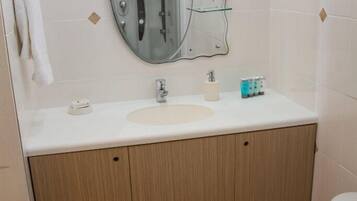 Un bagno con un lavandino bianco, uno specchio e un water.