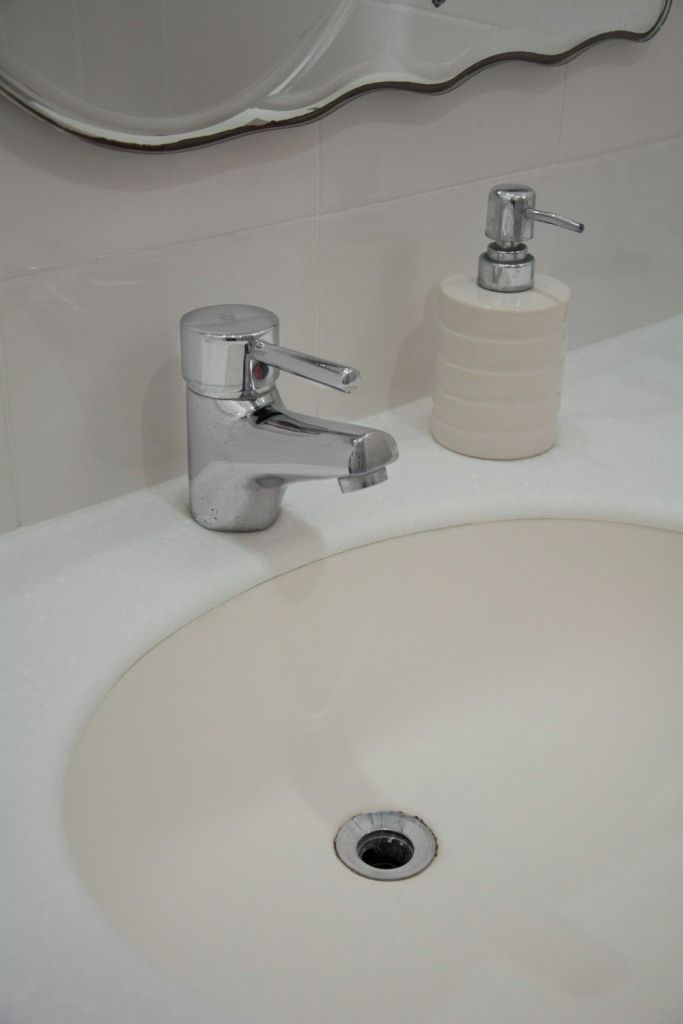 A bathroom sink with a chrome faucet and a soap dispenser.