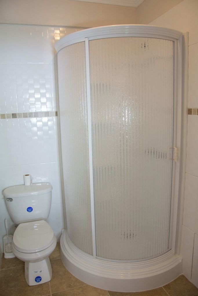 Un baño con inodoro, cabina de ducha y paredes con azulejos.