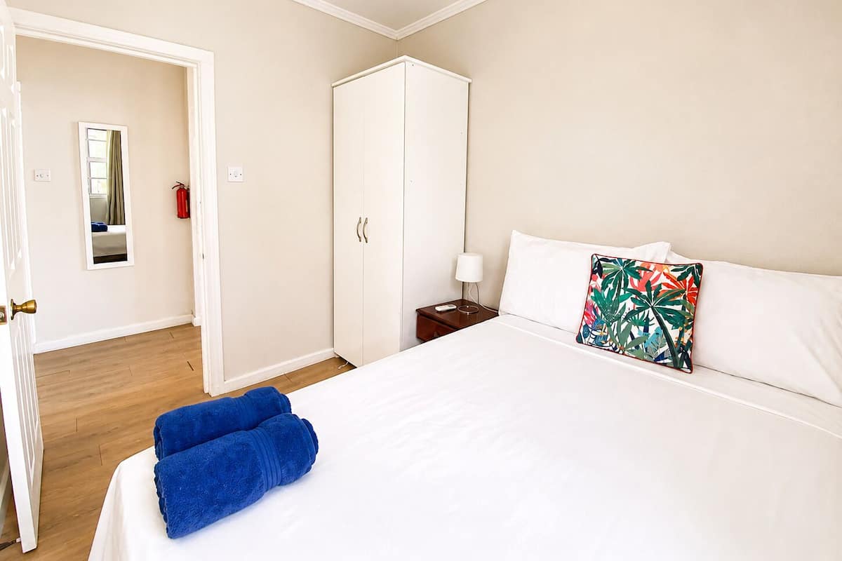 A hotel room with a bed, a wardrobe, a nightstand, a lamp, and a mirror.
