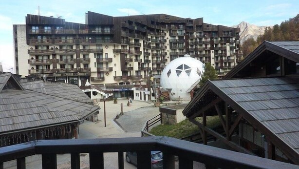 A multi-story hotel with a modern architectural design, featuring balconies and a central courtyard.