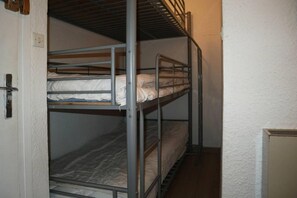 A bunk bed room with a door and a small cabinet.