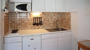 A compact kitchen with a microwave, sink, and a small refrigerator.
