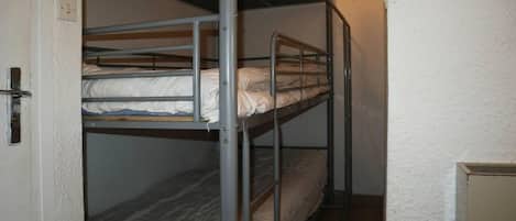 A bunk bed room with a door and a small cabinet.