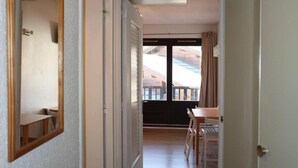 A corridor leading to a balcony with a table and chairs.