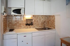 A compact kitchen with a microwave, sink, and a small refrigerator.