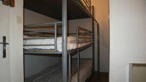 A bunk bed room with a door and a small cabinet.