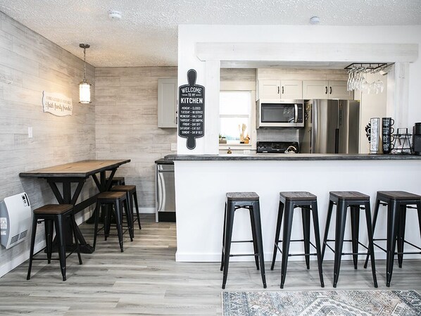 A modern kitchen with a wooden island, bar stools, and a welcome sign.