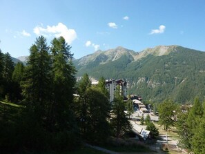 A mountain lodge with multiple buildings, surrounded by dense forest and mountains.