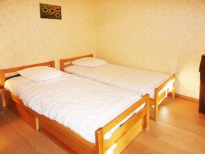 A room with two wooden beds, a small table, and a wall-mounted picture.