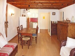 A cozy room with a wooden dining table, chairs, a sofa, and a cabinet.