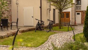 A cobblestone pathway leading to a building with a door and two bicycles parked outside.