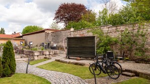 A courtyard with a stone wall, a paved path, and a bicycle.