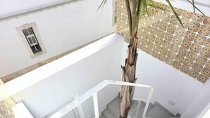 Eine Treppe mit weißer Handlauf, einem Blumentopf und einer Wand mit geometrischem Muster.