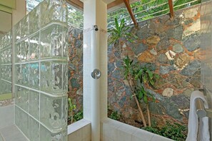 A bathroom with a stone wall, a glass shower enclosure, and a towel rack.