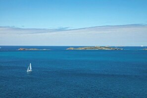A sailboat on a calm sea with distant land and a lighthouse.