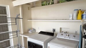 A compact laundry room with a washing machine, dryer, and a drying rack.