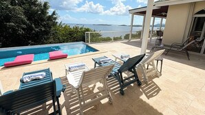 A poolside area with lounge chairs and a covered seating area.