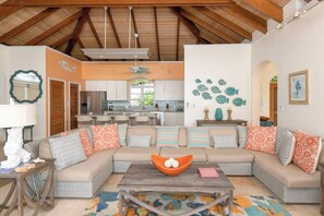 A spacious living area with a large sofa, a coffee table, and a kitchen in the background.