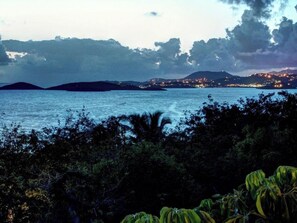 A coastal landscape with a view of the sea and distant city lights.