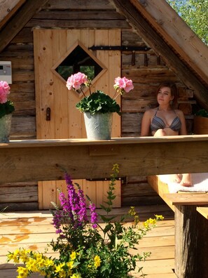 A wooden cabin with a balcony, a wooden door, and potted plants. - Wellness and relaxation with Icelandic sauna & massages (Wunsiedel)