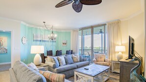 Una sala de estar con sofá, sillones, una mesa de centro y un mueble para televisión.