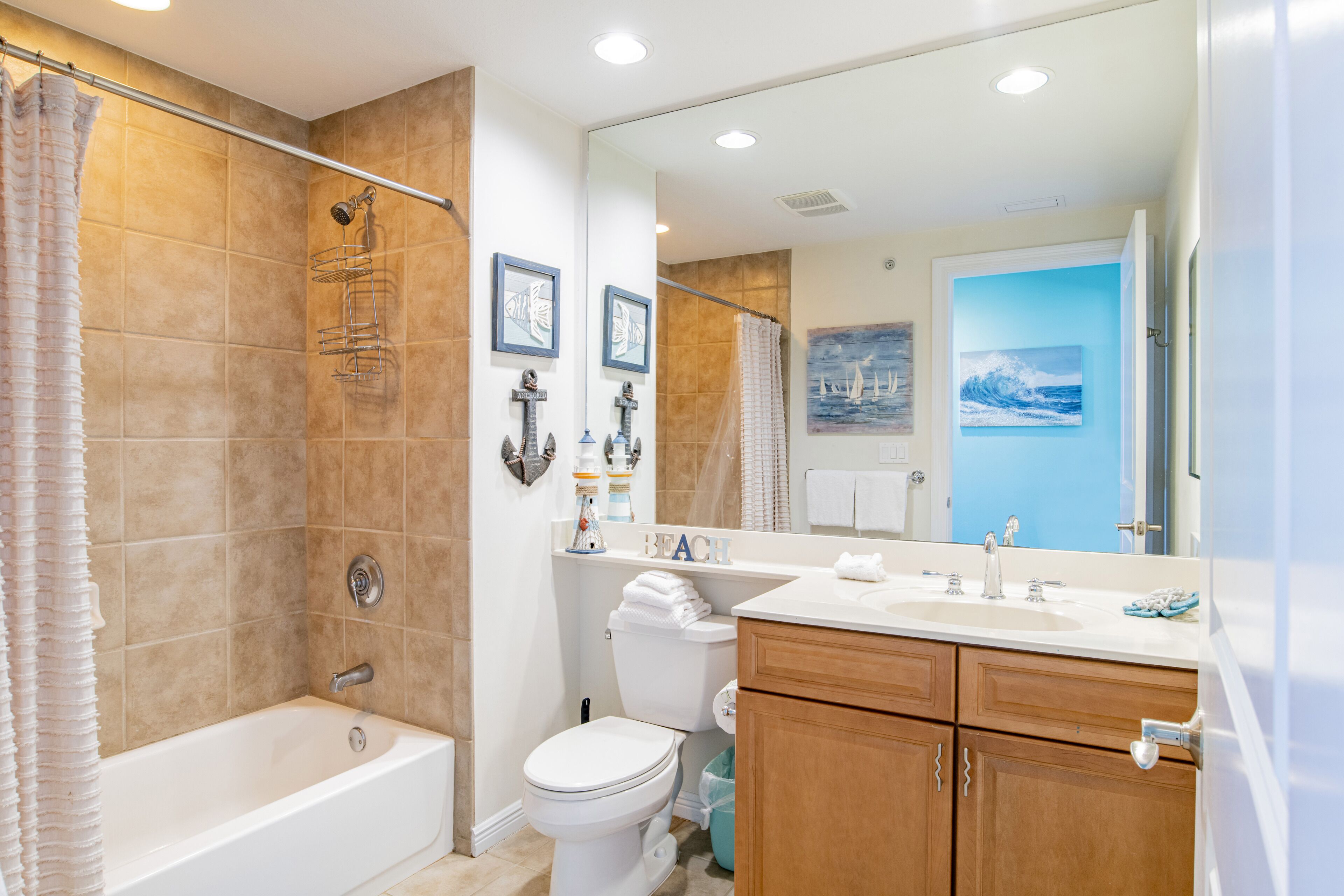 A bathroom with a bathtub, toilet, vanity, and a large mirror.