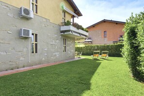 Un immeuble doté de climatiseurs, un balcon agrémenté de plantes, une pelouse bien entretenue et du mobilier d’extérieur.