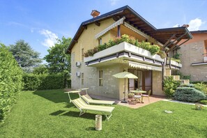 A two-story house with a balcony, a lawn, and a patio with outdoor furniture. - Regarda - appartment "Iris" in complex with swimming pool very close to the Lazise city centre (Lazise)