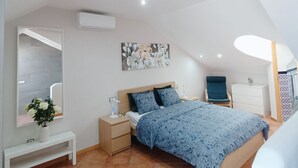 A bedroom with a bed, bedside tables, a dresser, a mirror, an air conditioning unit, and a ceiling light fixture. - Apartamento Idaira Paradise (Playa Paraíso)