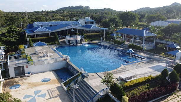Ein Resort mit großem Schwimmbecken, überdachtem Bereich und Blick auf die umliegende Landschaft.