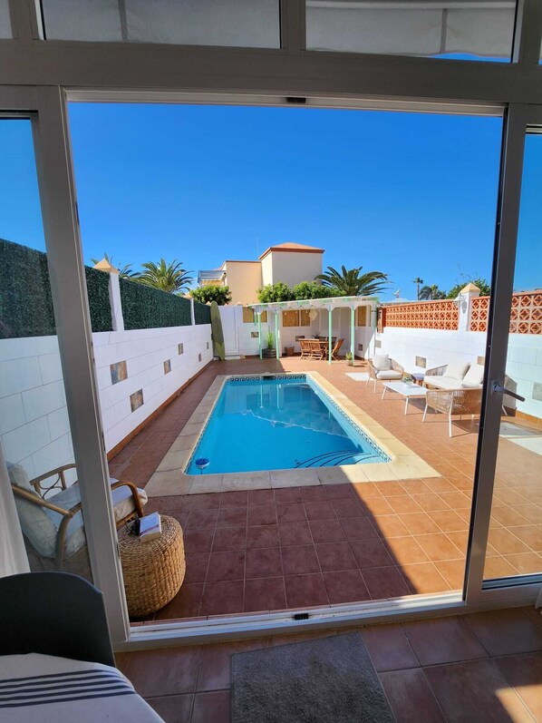 A pool area with a tiled deck, a small pool, and outdoor furniture.