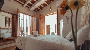 Un dormitorio con una cama grande, vigas de madera en el techo, un espejo y un ventanal con vistas.