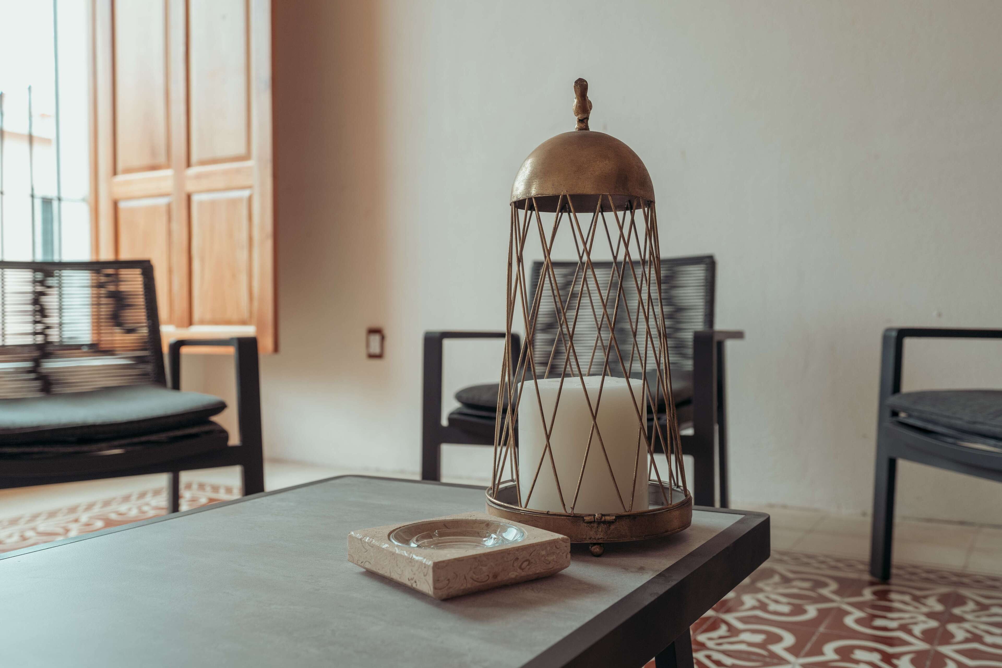 A table with a candle in a metal holder, a glass ashtray, and a patterned rug.