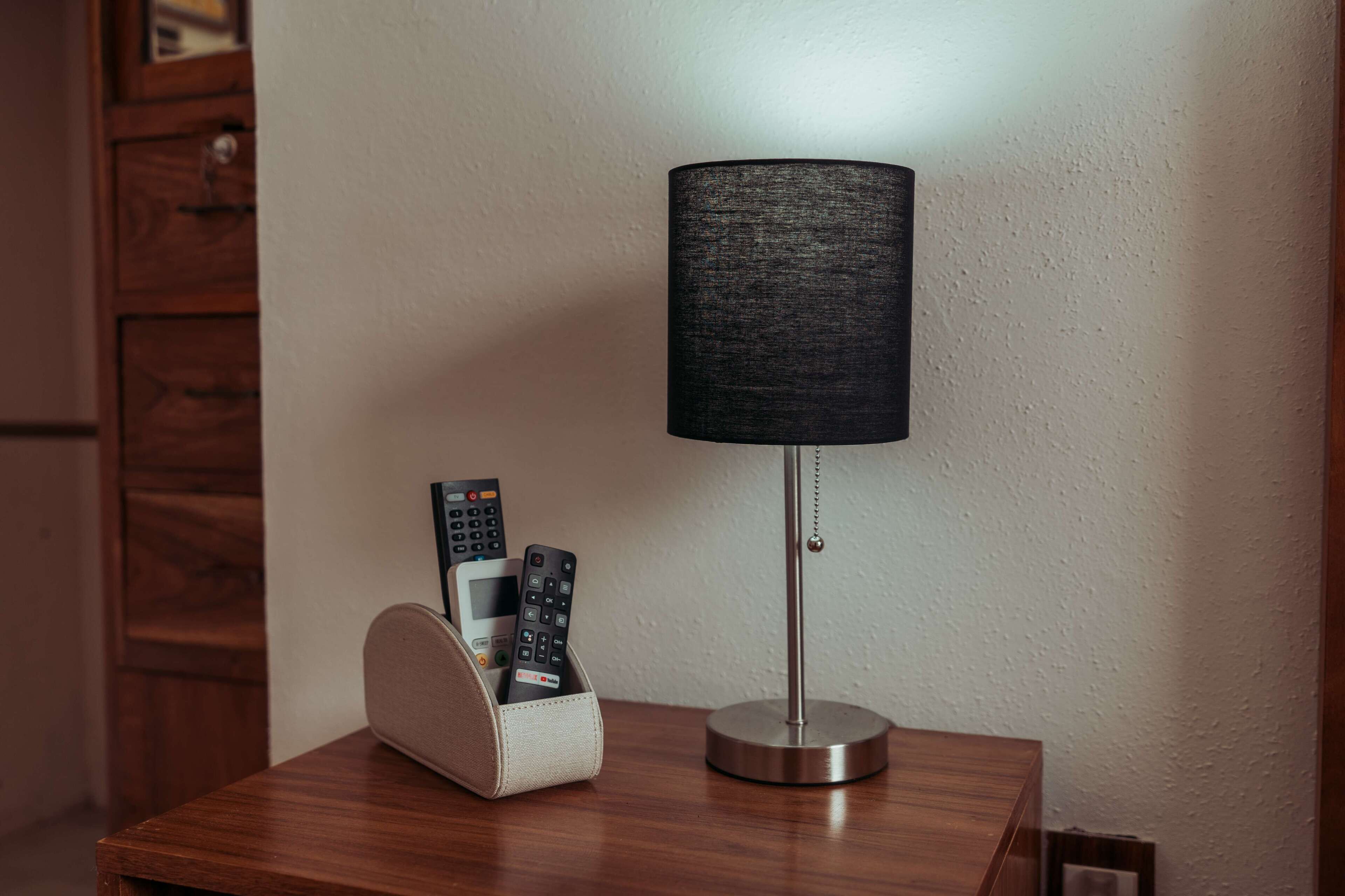 Una lámpara con pantalla negra sobre una mesa de madera.