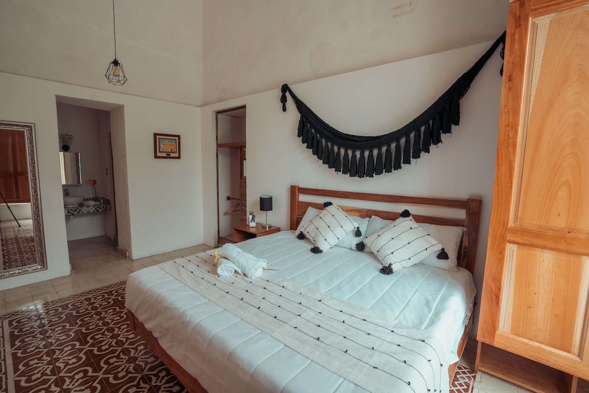 A bedroom with a large bed, a wooden wardrobe, and a hanging black tassel.