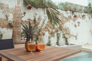 Een houten tafel met twee glazen amberkleurig drank en een ananas.
