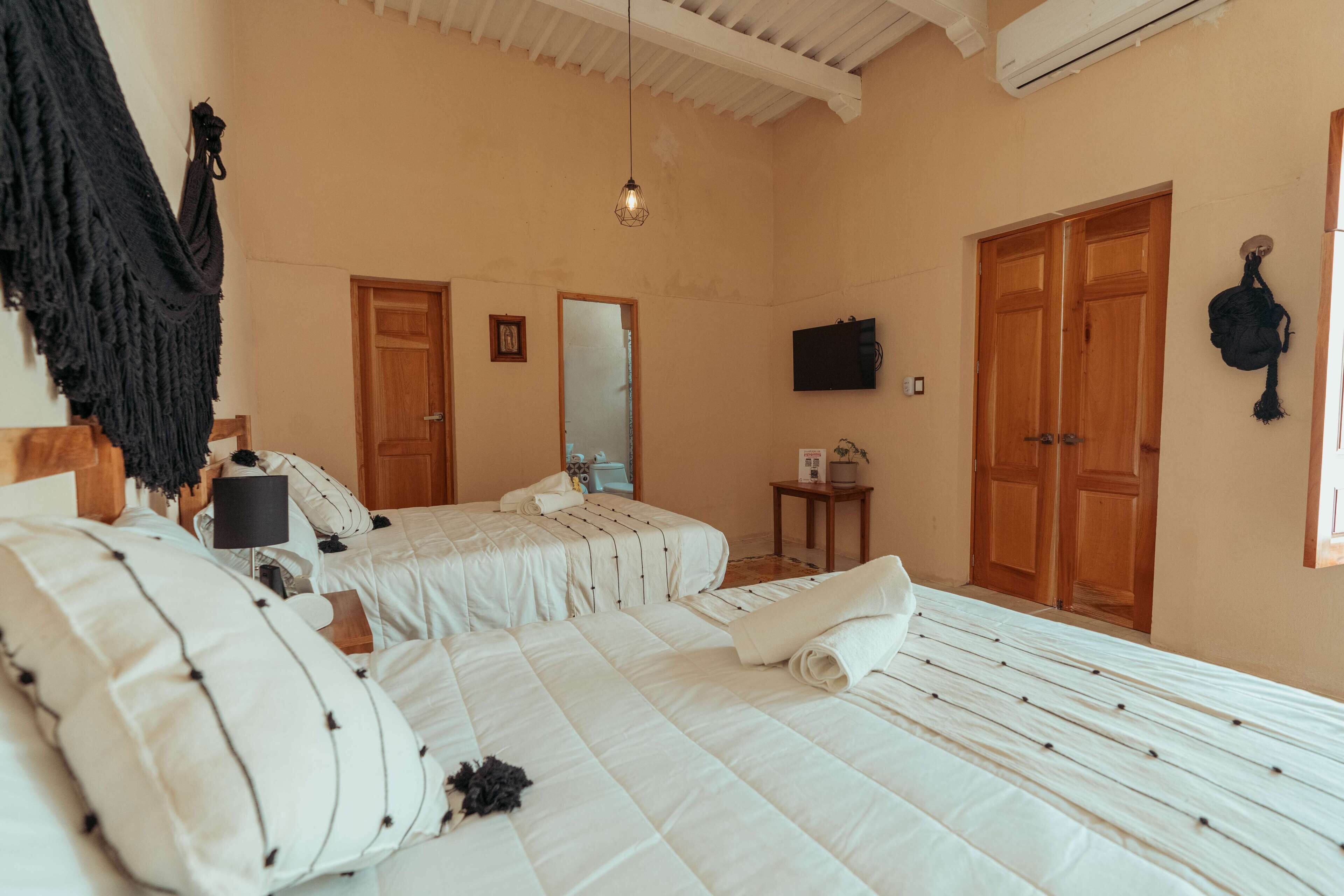 A bedroom with two beds, a TV, a mirror, and wooden doors.