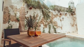 Una mesa de madera con dos vasos de un brebaje ámbar y una piña.