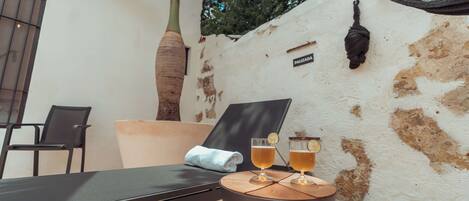 A sun loung Chair, a table with two glasses of beer, a palm tree, and a wall with a sign.