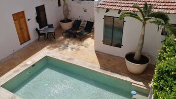 A swimming pool, outdoor seating, and potted plants.