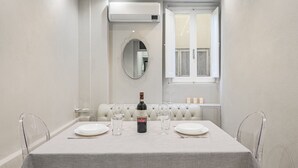 A dining room with a table set for two, a bottle of wine, and a mirror on the wall. - Live the Heart of Florence: Design Suite 30m from Ponte Vecchio and Pitti Palace (Firenze)