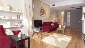 A modern living room with a red sofa, a TV, a bookshelf, and a fireplace. - Sant Pau 5 - Superb 3-bedroom apartment in central Barcelona (Barcelona)